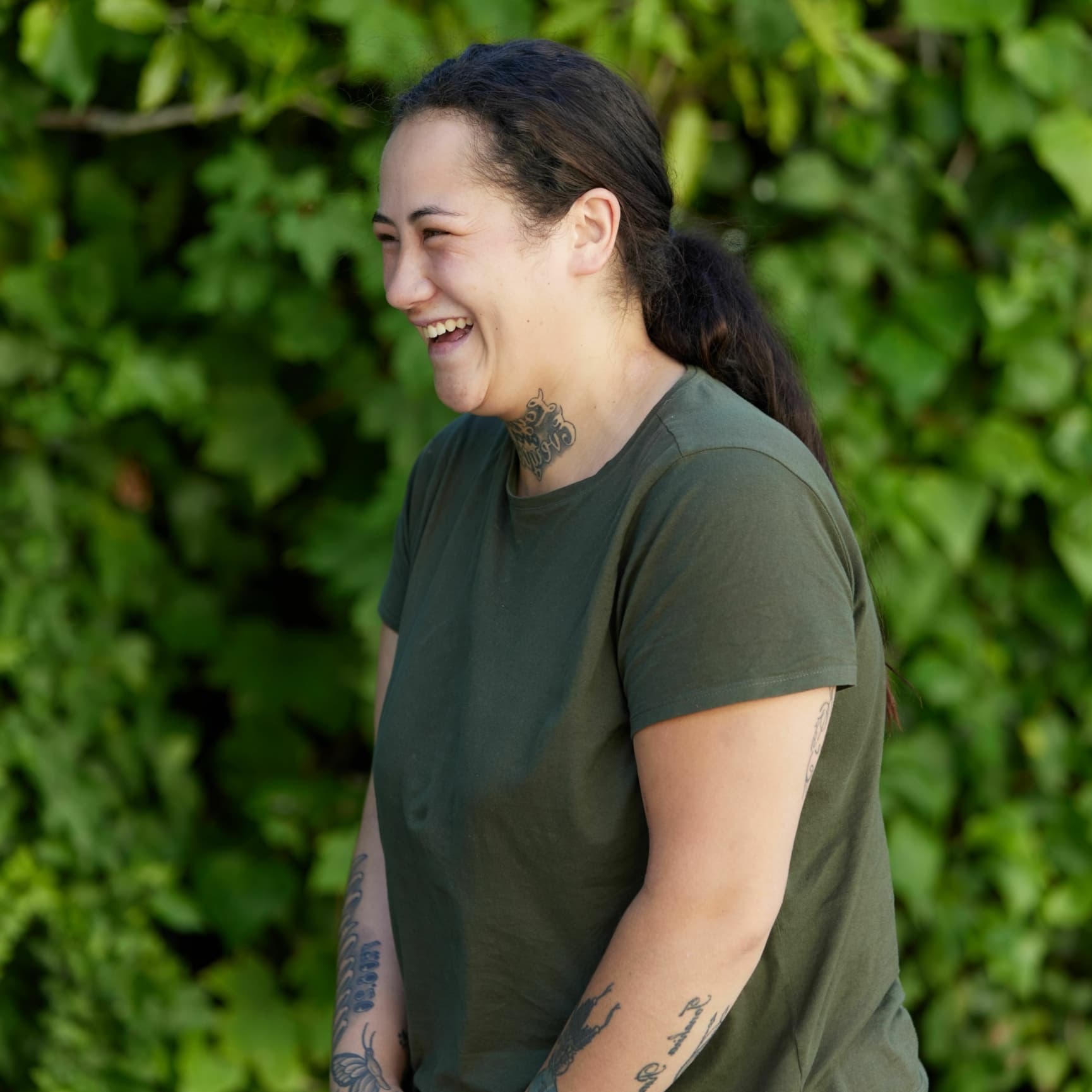 A picture of a young woman standing and smiling to the left.