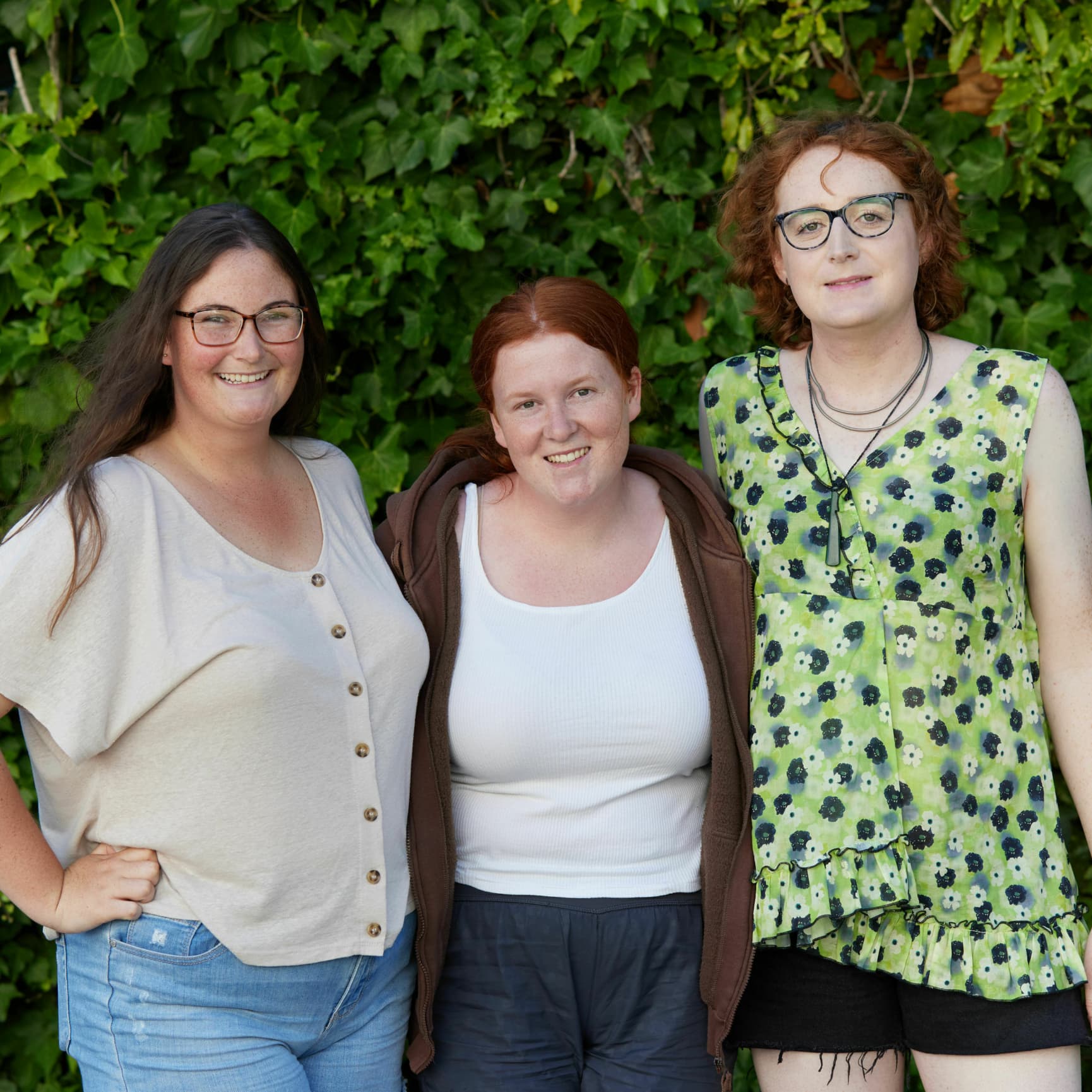 A picture of three young people standing outside and smiling at the camera